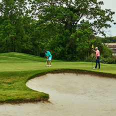 A man attempts a putt at the Westin course while another man holds the hole flag