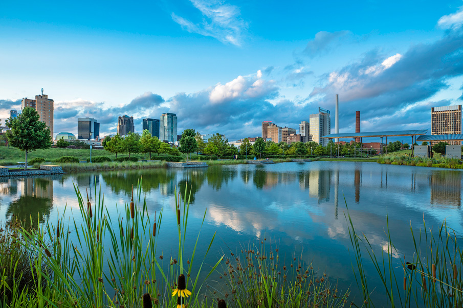 Daytime view of the Birmingham skyline from Railroad Park with a pond in the foreground